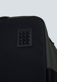 Zaino nero con un pannello in gomma testurizzata a forma di piramide. Realizzato in tessuto resistente con dettagli lisci.