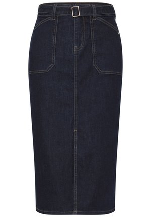 Kvinde iført mørk denimsnørk med forlommer og bæltedetalje, bærende en stribet vævet skuldertaske.