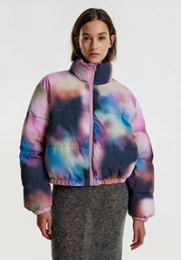 Pufferjack die voorzien is van een multicolor gradiëntpatroon met blauwe, roze en paarse tinten. Het heeft een hoge kraag en een voorkant met rits.