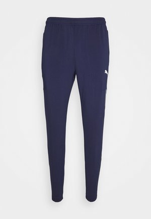 Navy blue Puma athletic pants with elastic waistband and slim tapered legs, featuring a white Puma logo on the upper thigh.