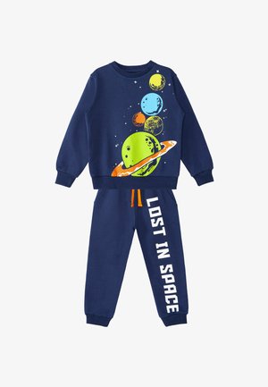 Svetlo modra dukserica in hlače. Vsebuje barvite grafike planetov in besedilo "POGUBLJEN V PROSTORU" v beli barvi. Narejeno iz mešanice mehke bombažne tkanine.