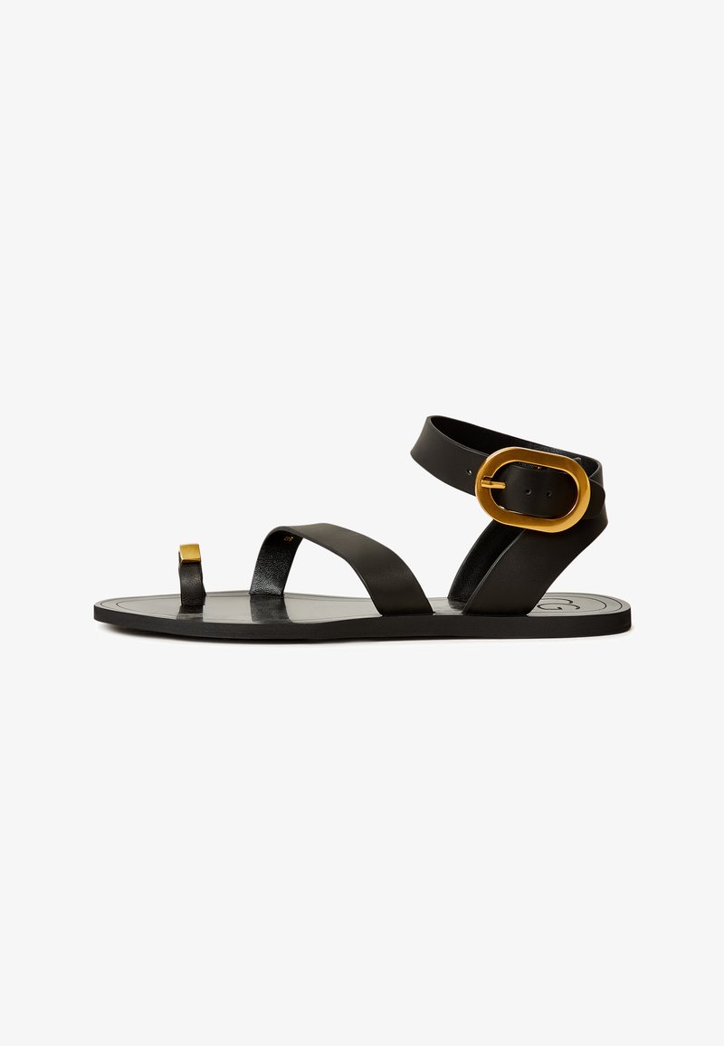 Sandal din piele neagră, cu două curele late, o curea îngustă la degete și un accent cu cataramă aurie. Talpă plată cu un branding subtil pe talpa interioară.