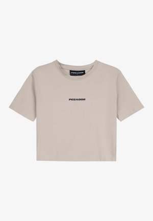 T-shirt cropped bege feita de algodão com decote redondo e mangas curtas. Apresenta o logótipo "PEGADOR" impresso a preto na parte da frente.