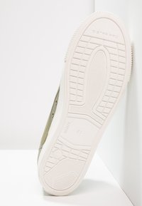 Baskets en toile verte avec une semelle en caoutchouc blanche, dotées d'une semelle extérieure texturée et d'œillets métalliques. Taille 41 embossée sur la semelle.