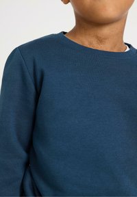 Felpa a maniche lunghe blu scuro con scollo rotondo, realizzata in un morbido tessuto testurizzato. Presenta una vestibilità classica e rilassata e un colletto a costine.