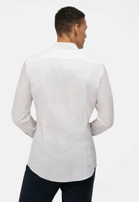 Witte blouse met lange mouwen van een gladde stof, met een standaard kraag, subtiele glans en een gebogen zoom. Geen zichtbare patronen of accenten.