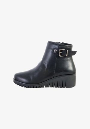 Bottine en cuir noir à bout rond, avec une boucle décorative sur le côté et une semelle en wedge texturée présentant des rainures horizontales.