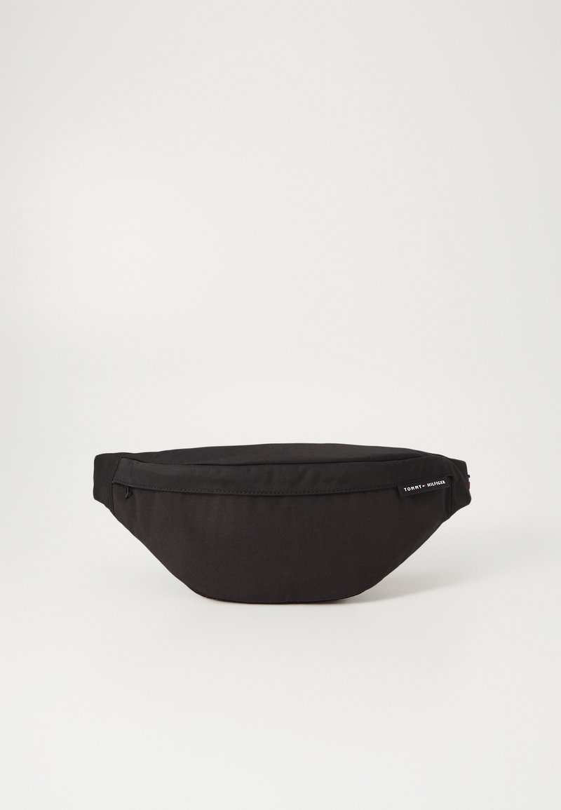 Riñonera negra de nylon con un diseño curvado, cierre de cremallera y etiqueta con el logo. Presenta una textura suave y una forma compacta para el almacenamiento.