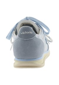 Zapatilla de ante azul claro con detalles en blanco, cordones visibles, suela beige y logotipo "victoria" en la lengüeta del talón, vista desde atrás.