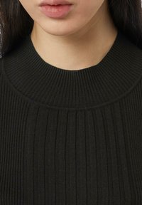 Schwarzer gerippter Pullover mit hohem, rundem Kragen, der ein strukturiertes Muster und weichen Stoff aufweist, mit vertikalen Linien und einem glatten Finish.