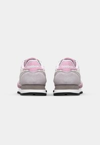 Tênis Reebok com parte superior de camurça rosa e cinza, apresentando um logo branco, detalhes em malha e um solado de borracha preta.