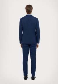 Merevaigist koos tekstuuriga kangaga, millel on üks lõhe, slim-fit lõikega ja sobituvad püksid. Mustad pidulikud kingad täiustavad välimust.