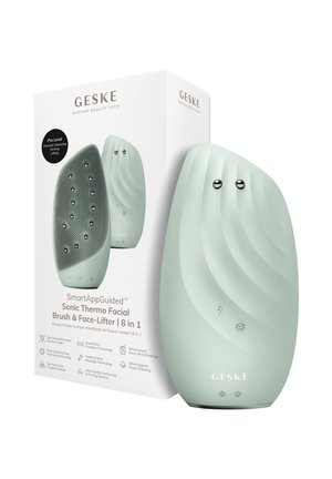 Brosse faciale intelligente vert menthe élégante avec surface en silicone texturée et nœuds métalliques, présentée à côté de sa boîte blanche.
