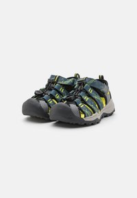 Sandali sportivi con un design nero e giallo, dotati di cinturini regolabili, punta rinforzata e suola in gomma robusta per una buona aderenza.