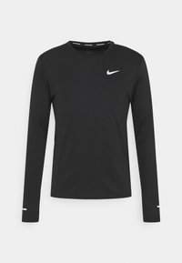 Långärmad svart träningsskjorta, tillverkad av slät tyg, med en vit Nike-logotyp på bröstet och små vita detaljer på ärmarna.