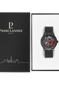 Reloj de metal negro con correa de malla, que presenta una esfera esqueletica, acentos rojos y amarillos, y un logotipo de marca dentro de una caja negra.