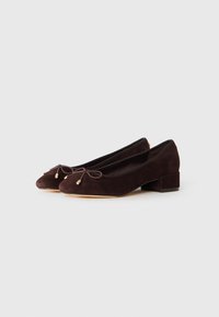 Dark brown suede low-heeled ballet shoes with rounded toes and small bow accents on a white background.