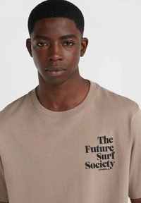 Beige t-shirt made of cotton, featuring a round neck and short sleeves, with black text: "The Future Surf Society" and logo.