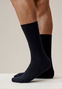 Ciemnoniebieskie skarpetki bawełniane z prążkowanym mankietem, dopasowanym krojem i bezszwowym palcem. Prezentowane na neutralnym tle.