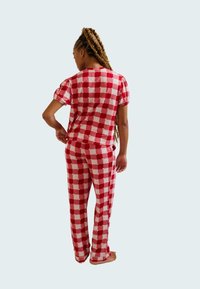 Red and white checkered pajama set with a short-sleeve top and long pants, displayed from the back. Soft fabric with puffed sleeves.