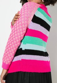 Gebreide trui met een mix van patronen en kleuren: roze, muntgroen, zwart en lavendel strepen, textuurdetail in het roze op de schouder, geribbelde zoom.