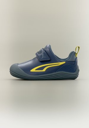Barnets mørkeblå sneaker med gul accent, velcrolukning og trækflap på grå sål mod en ensfarvet baggrund.
