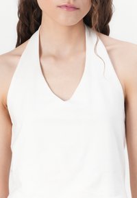 White halter top featuring a V-neck design, made of smooth fabric with a clean seam. No patterns or embellishments are visible.
