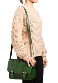 Borsa a spalla verde in pelle con texture lucida, dotata di chiusura a pattina, due cinture frontali e una lunga tracolla regolabile.