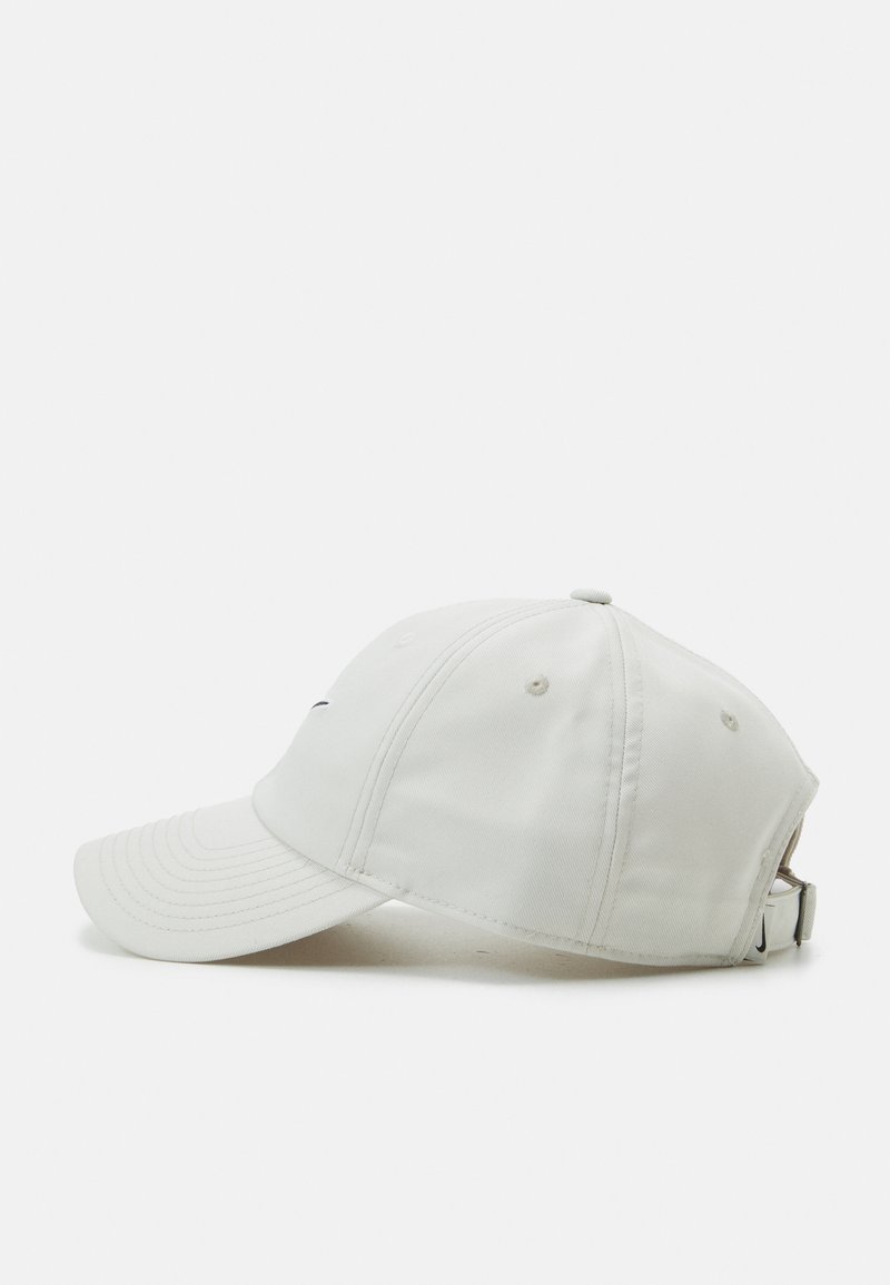 Gorra de béisbol blanca con un borde curvado, adornos cosidos y una correa ajustable metálica. La tela tiene una textura suave y mate.
