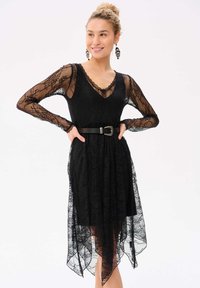 Zwart kanten jurk met lange doorzichtige mouwen, V-hals, getailleerde taille met een riem en een high-low zoom met delicate kantdetails.