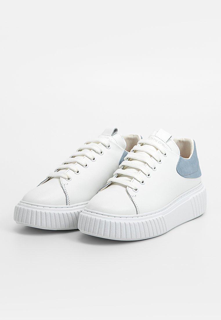 Weiße Kunstleder-Sneaker mit hellblauen Wildlederakzenten, flachen Schnürsenkeln und dicken weißen Gummisohlen mit gerippter Textur.