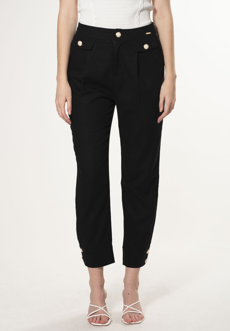 Schwarze hochtaillierte Hosen mit Seitentaschen und goldenen Knopfakzenten, mit einem taillierten Schnitt und umgelegten Säumen. Der Stoff wirkt glatt.