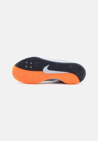 Nike fodtøj med en struktureret sort ydersål og en orange detalje. Har et sølvfarvet swoosh-logo på siden.
