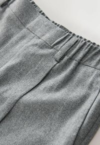 Gray sweatshirt fabric with a soft texture, featuring an elastic waistband and subtle stitching details. Close-up view of the material.