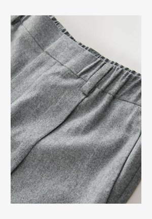 Pelēka sporta krekla audums ar mīkstu tekstūru, ar elastīgu jostu un smalkiem šuvju detaļām. Tuva skats uz materiālu.