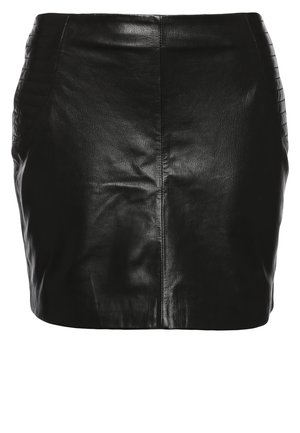 Kobieta w czarnej skórzanej kurtce i spódnicy, białej bluzce z wzorzystym kołnierzykiem, czarnych rajstopach, botkach za kostkę, trzymająca czarno-białą kopertówkę.