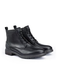 Botas de cuero negro con un acabado suave, diseño de cordones, suela de goma de contraste y lengüetas en la parte superior para ponerlas y quitarlas con facilidad.
