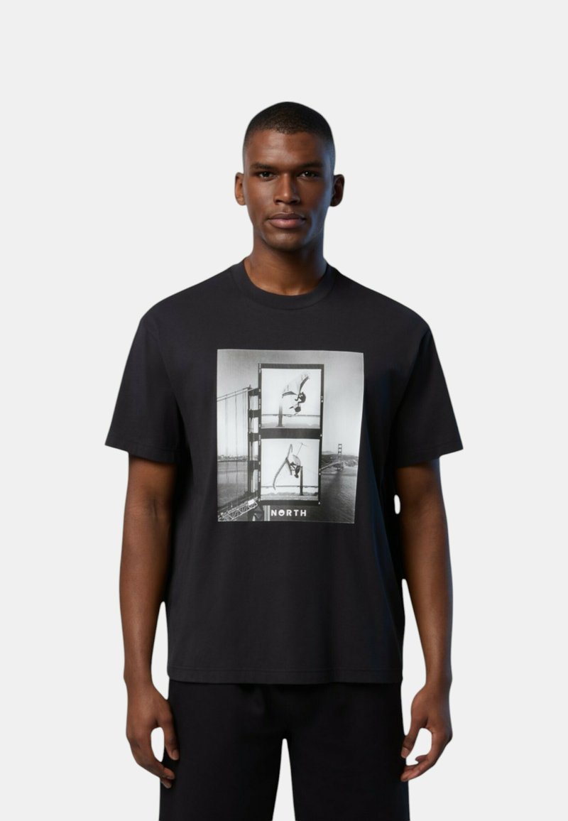 T-shirt in cotone nero con stampa grafica frontale che mostra foto e la parola "NORTH" in basso; design morbido, colletto rotondo, maniche corte.