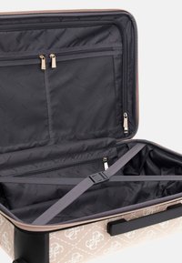 Kovokas vankka matkalaukku kermanvärisenä, jossa on tikattu kuvio ja mustat yksityiskohdat. Sisäpuolella on vetoketjullinen verkkoaukko ja säädettävät hihnat.