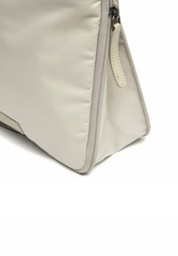 Borsa di stoffa beige a forma triangolare, con zip e linguetta in pelle. Superficie testurizzata con dettagli di cucitura visibili.
