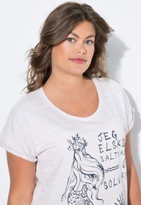Weißes T-Shirt mit kurzen Ärmeln, das ein Meerjungfrauen-Motiv und Textdruck zeigt. Der Stoff hat dünne horizontale Streifen und einen lockeren Halsausschnitt.