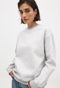 Lichtgrijze sweatshirt met een ronde hals, geribde mouwen en een relaxte fit. De stof lijkt zacht met een subtiele textuur. Casual ontwerp.