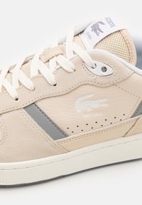 Beige semsket og lær sneakers med grå detaljer, rund tå, teksturert overdel og hvite lisser. Har logo og perforerte detaljer.
