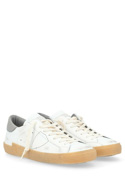 Sneaker bianchi in pelle con retro grigio testurizzato, lacci crema e suola in gomma color caramello. Presentano motivi cuciti e un design minimale.