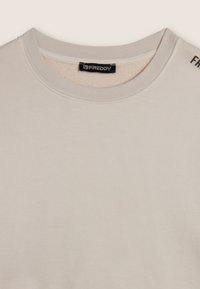 Felpa beige chiaro realizzata in tessuto morbido, con scollatura rotonda e logo "FREDDY" sulla spalla. Texture liscia con cuciture minime.