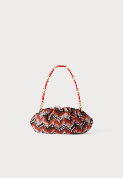 Handtasche mit rot-schwarzem Zickzackmuster und gerafftem Design, ausgestattet mit einer goldenen Kette und roten Kunststoffverlinkungen. Strukturierte Stoffoberfläche.