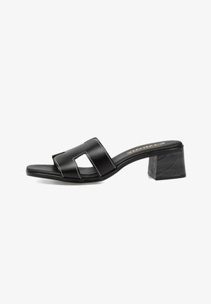 Sandalia mule negra de punta abierta con tira ancha recortada y tacón bloque, presentada sobre fondo blanco.