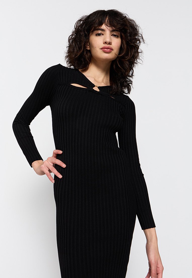 Vestido de punto negro con canalé y mangas largas, que presenta un exclusivo detalle en forma de corte en el escote y una silueta ajustada.