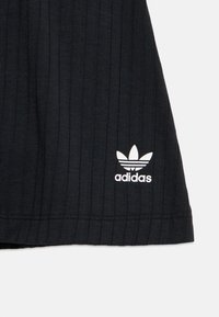 Μαύρο ριμπ ύφασμα μπλουζάκι με λευκό λογότυπο Adidas και τρεις ρίγες κοντά στο τελείωμα. Η υφή είναι λεία με κάθετες γραμμές.