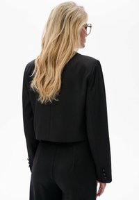 Czarna krótka marynarka z długimi rękawami, zapinanymi mankietami i gładką fakturą. Charakteryzuje się dopasowanym krojem i minimalistycznym stylem.